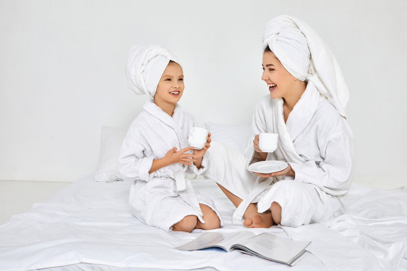 Mother and Daughter in White Bathrobes Drinking Tea